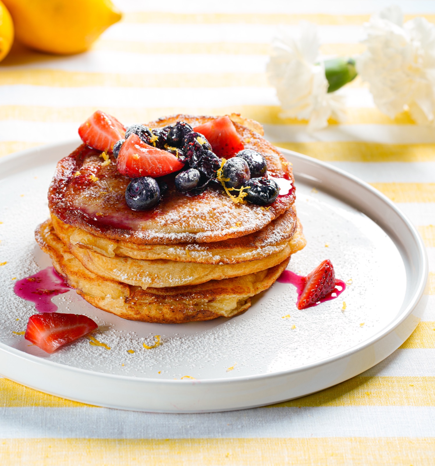 Pancakes with berries, powdered sugar, and lemon zest