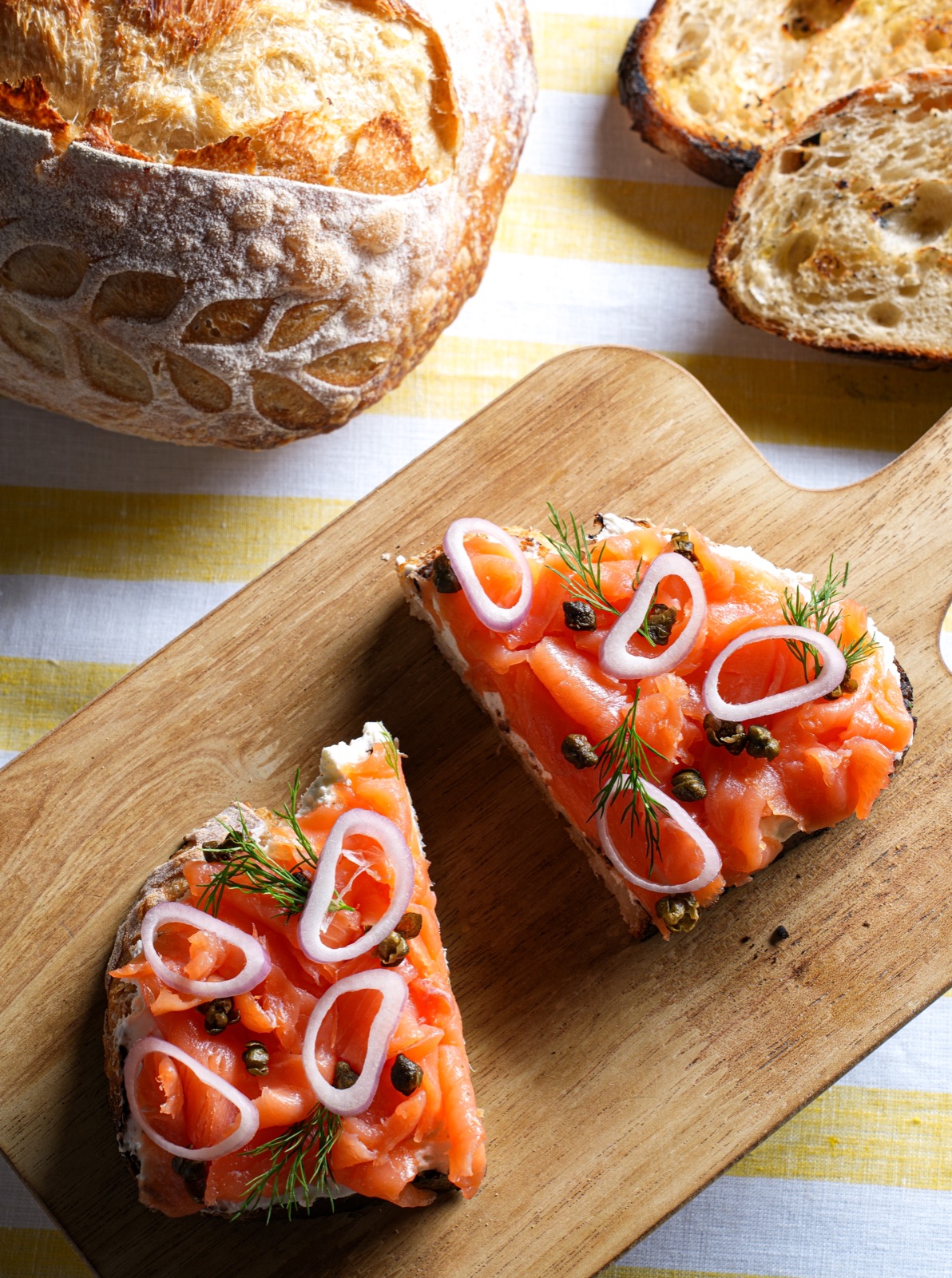Two pieces of smoked salmon toast beside sourdough bread