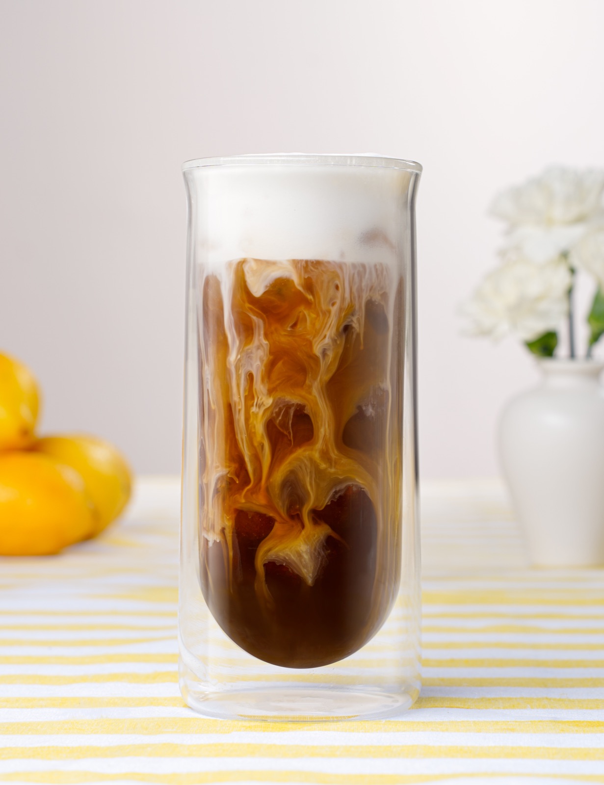 Iced coffee with cream swirling through the glass