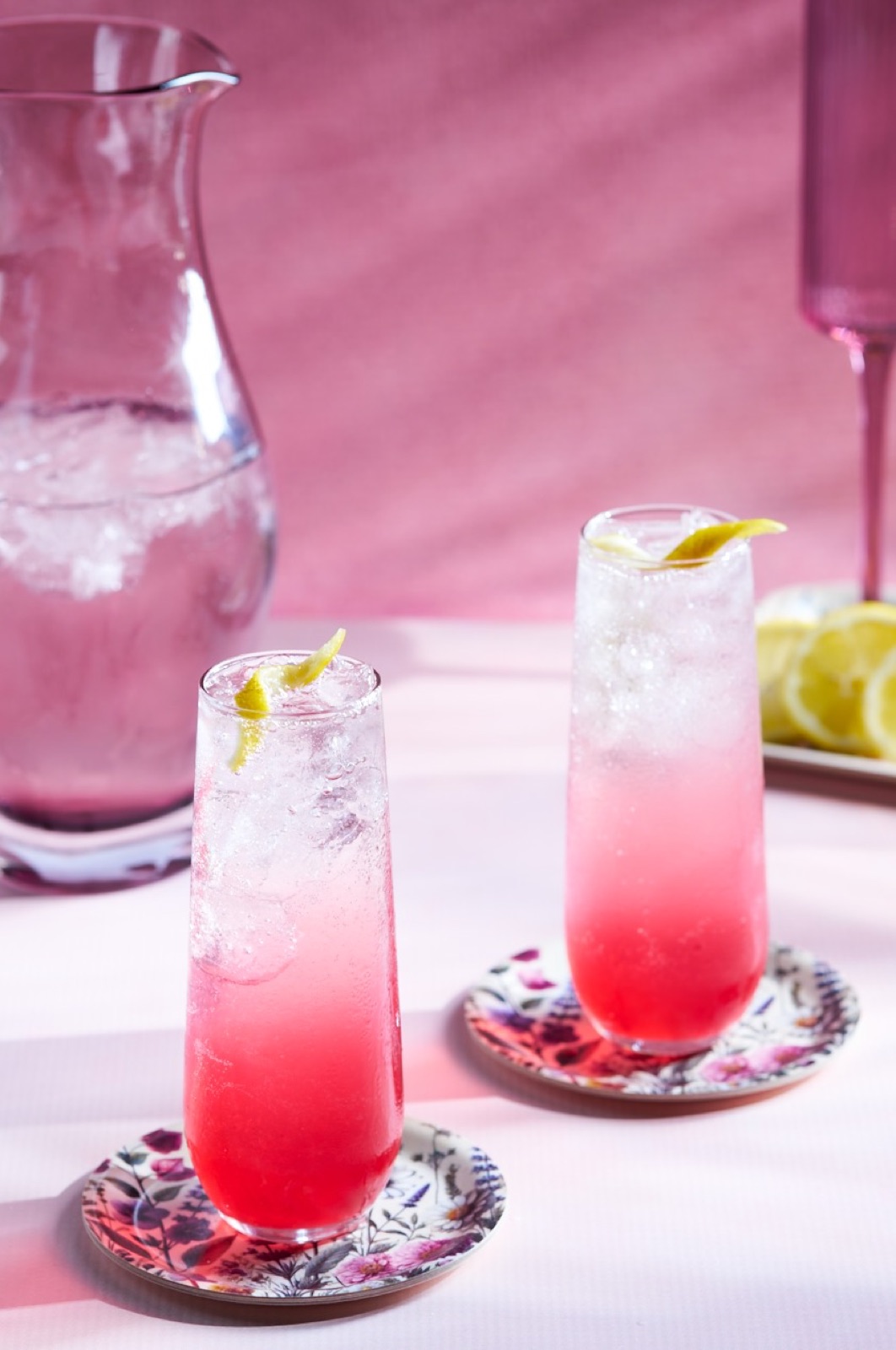 Two sparkling pink drinks with lemon twists