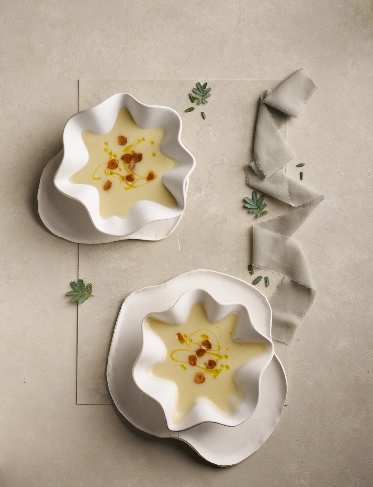 Two bowls of pale soup in sculptural white dishes